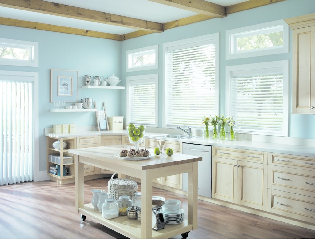 A kitchen with white wooden blinds on the windows