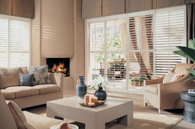 A living room with a sliding glass door featuring plantation shutters.